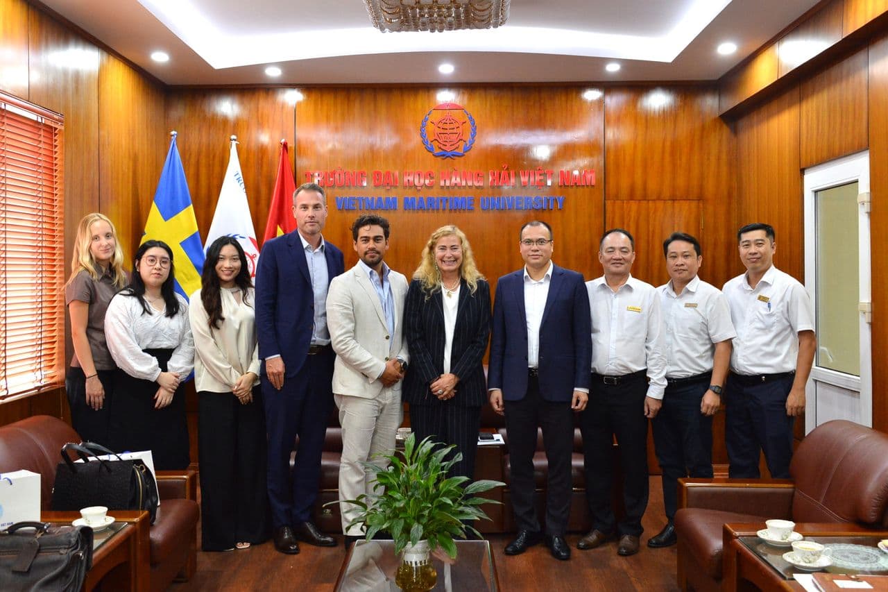 A group of professionals standing together in a wood-paneled meeting room at Vietnam Maritime University
